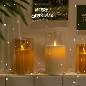 Three LED electronic candles in glass jars on a festive Christmas snowy table background