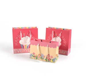 Three colorful paper gift bags with cupcakes patterns and ribbon handles for packaging