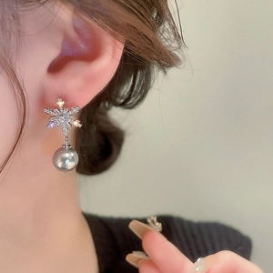 Detail of silver snowflake earring with zircons and grey pearl on model's ear