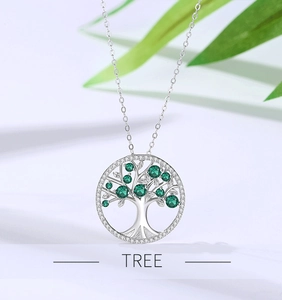 Macro shot of silver Tree of Life necklace featuring vibrant green crystal inlays