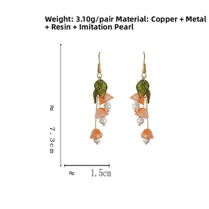 Detailed view of long pink bell flower earrings with green leaves and pearl accents