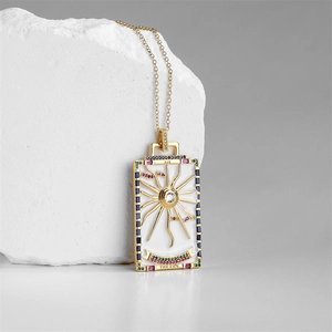Macro detail of gold tarot Sun pendant with XIX engraving and colorful gemstones