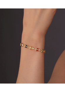 Close-up of gold butterfly bracelet with colorful enamel charms on a woman's wrist
