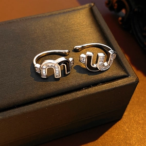 Detailed view of silver double-layered serpent earrings with zircon and black enamel M letter