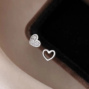 Orecchini a lobo a cuore in argento 925 con zirconi su una superficie beige liscia