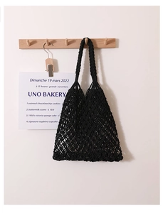 Detail of black handmade crochet tote bag featuring large mesh design and dual straps