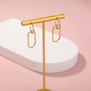 Close-up of golden geometric double hoop earrings with mirror finish on display stand