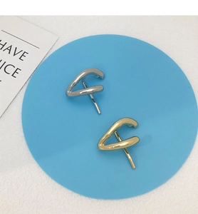Detail of twisted geometric alloy hair clips in gold and silver finish on a blue mat