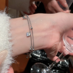 Close-up of double-layer silver bracelet with heart zircon charm and metal beads