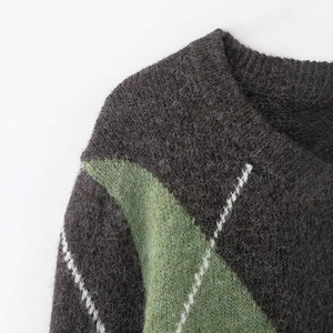 Pull en maille à col en V à motif de losanges vert et gris foncé avec une texture duveteuse