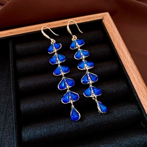 Macro view of long vintage tassel earrings with deep blue heart stones in wooden jewelry box