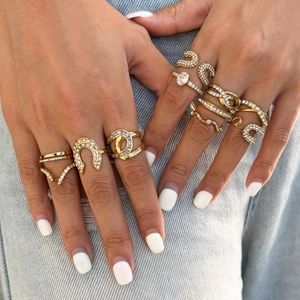 Gold-tone stackable ring set with zircon accents and horseshoe charm on denim background