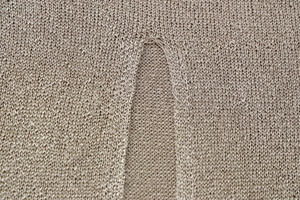 Macro detail of breathable light brown knitted fabric with fine mesh texture and split seam