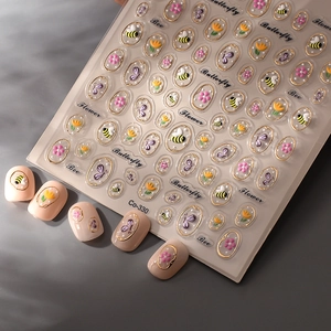 Gros plan d'autocollants 3D gaufrés abeilles et fleurs sur des ongles rose poudré