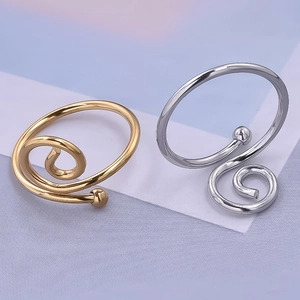 Detail view of spiral open rings in polished gold and silver finishes on textured background
