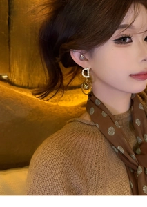Close-up of a model wearing a gold letter D earrings with zircon and ball pendant