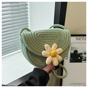 Dettaglio della borsa a sella intrecciata verde menta con fiore 3D e tracolla in corda
