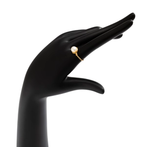 Detail of handcrafted wire-wrapped pearl ring in gold finish on black model hand