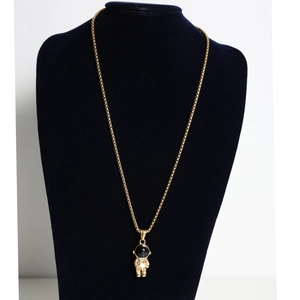 Detail of gold astronaut pendant with black visor and star motif on a display stand