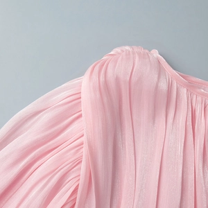 Detail of pink pleated chiffon dress featuring subtle pearlescent shimmer fabric