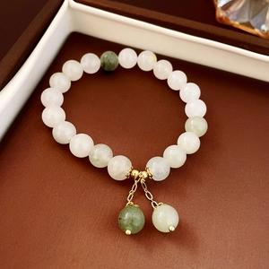 Detail of beaded natural stone bracelet with lotus seed charm and gold chains