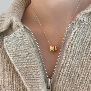 Elegant 925 sterling silver gold triple-ring necklace with zircons on a knit background