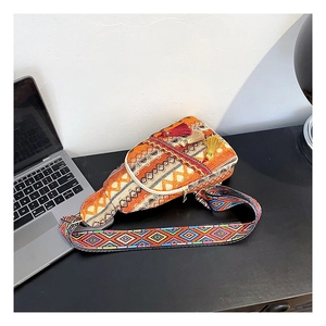 Close-up of geometric woven pattern with red and yellow tassels on ethnic chest bag