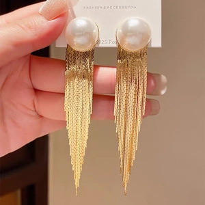 Macro shot of long gold tassel earrings with round pearl and S925 silver posts on a card