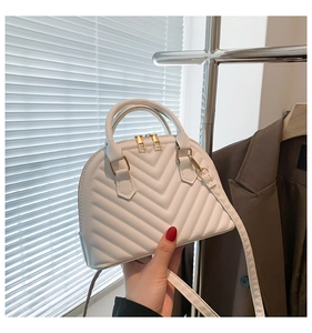 Detail of white quilted shell bag featuring gold zippers and detachable leather strap