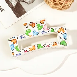 Macro shot of large rectangular hair claw clip with colorful heart print on white base
