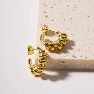18k gold plated stainless steel C-shape twisted spring earrings on a beige stone surface