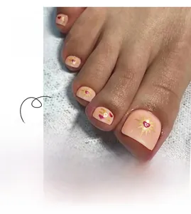 Detail of pink press-on toenails with gold stars, moon, and heart designs for pedicure