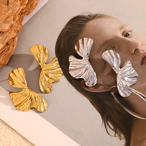 Artistic display of ginkgo leaf earrings in gold and silver finish on vintage paper