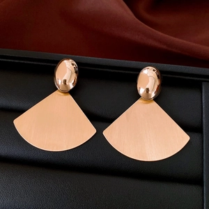 Close-up of rose gold fan-shaped earrings with brushed metal texture and oval studs