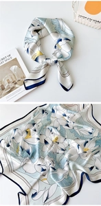 Detailed pattern of lotus print silk scarf with navy blue edges and smooth texture