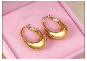 Close-up of polished gold teardrop hoop earrings in a pink velvet jewelry gift box