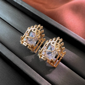 Detail of luxury gold earrings with emerald cut zircon and intricate vine metalwork