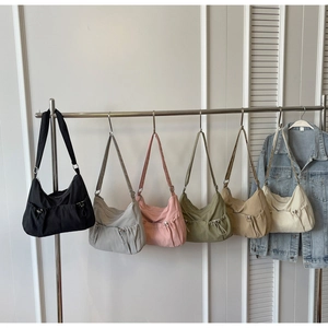 Close-up of nylon crossbody bags featuring pleated texture and side drawstring details