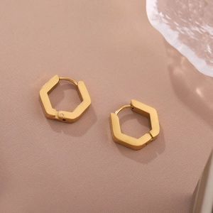Polished 18K gold-plated hexagonal earrings on a soft pink textured fabric background