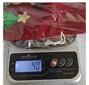Detailed view of Christmas burlap wine bag showing 40g weight on a digital scale.