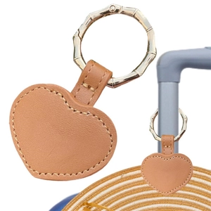 Close-up of heart-shaped PU leather hat clip with bamboo-style metal clasp on suitcase
