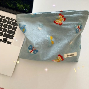 Detail of light blue cosmetic bag with colorful butterfly embroidery on desk