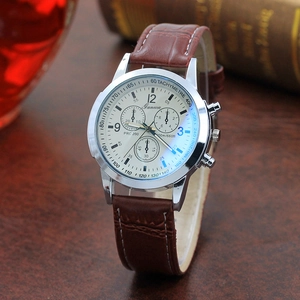 Detail of classic men's chronograph watch with brown leather strap on a wooden desk
