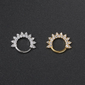 Close-up of silver and gold marquise zircon ear rings on a black textured background