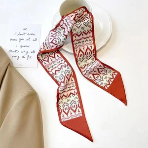 Detail of red and grey geometric silk scarf draped near a coffee cup and blazer