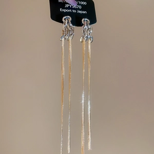 Détail de longues boucles d'oreilles pompons dorées avec poinçon argent 925 de luxe