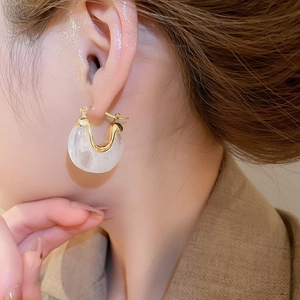 Gros plan de boucles d'oreilles vintage en U avec métal doré et résine texture marbre