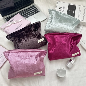 Macro shot of stylish velvet toiletry bags in various colors on an office desk