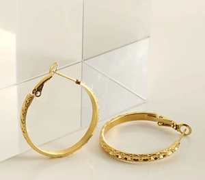 Detailed view of golden stainless steel hoop earrings with textured diamond patterns