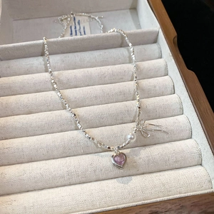 Detail of silver S925 necklace with pink heart pendant and bow in a jewelry box